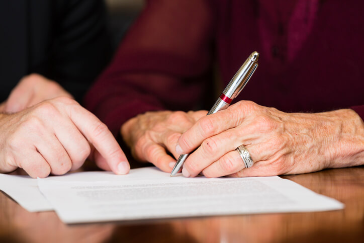 Older woman signing Medicaid documents