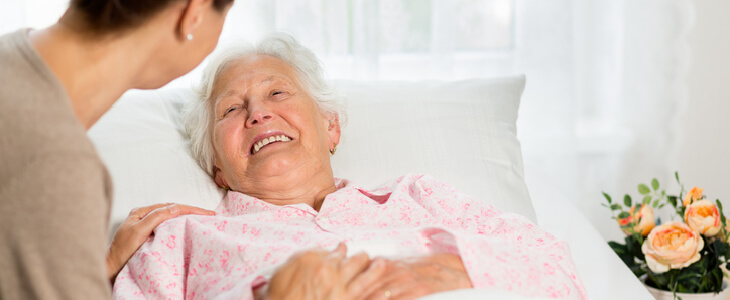 old woman smiling while looking at her caretaker