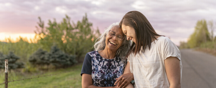 Elder woman laughing while holding onto her daughter